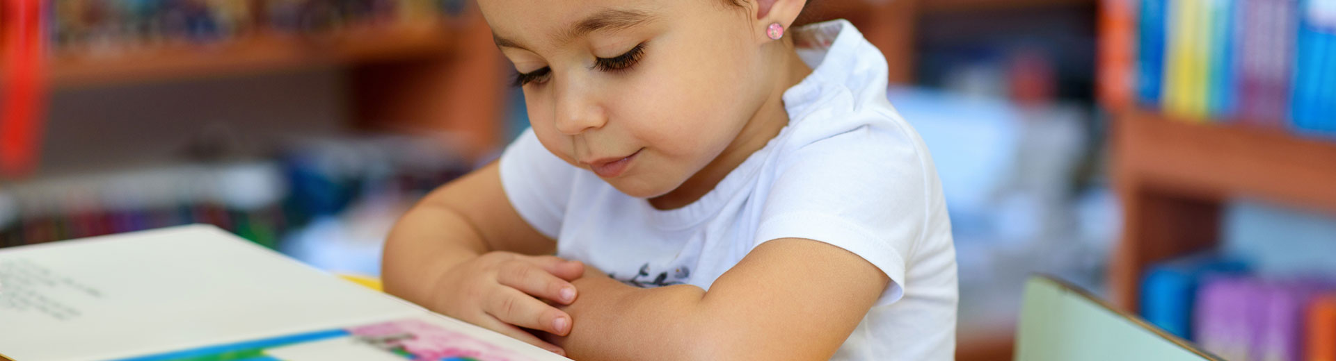 Little girl reading a book in a library